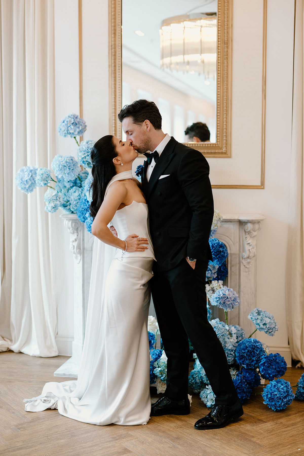 Bride and groom kissing in front of blue hydrangea wedding styling at The Exchange Glasgow fireplace