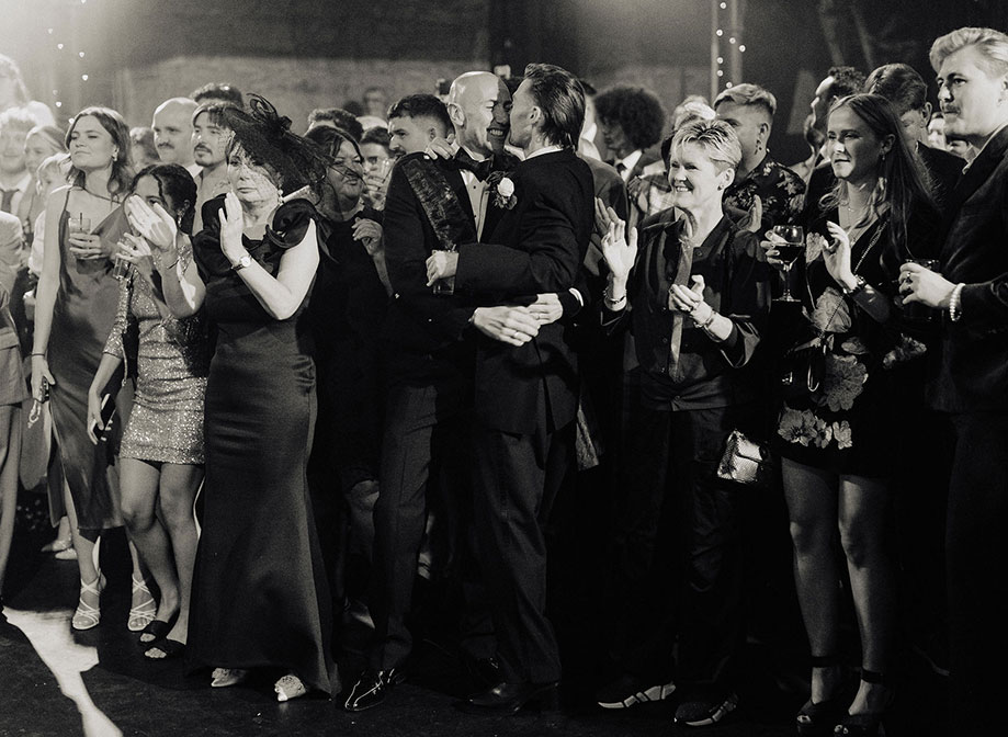 David And Alistair Black And White Grooms Embracing With Guests