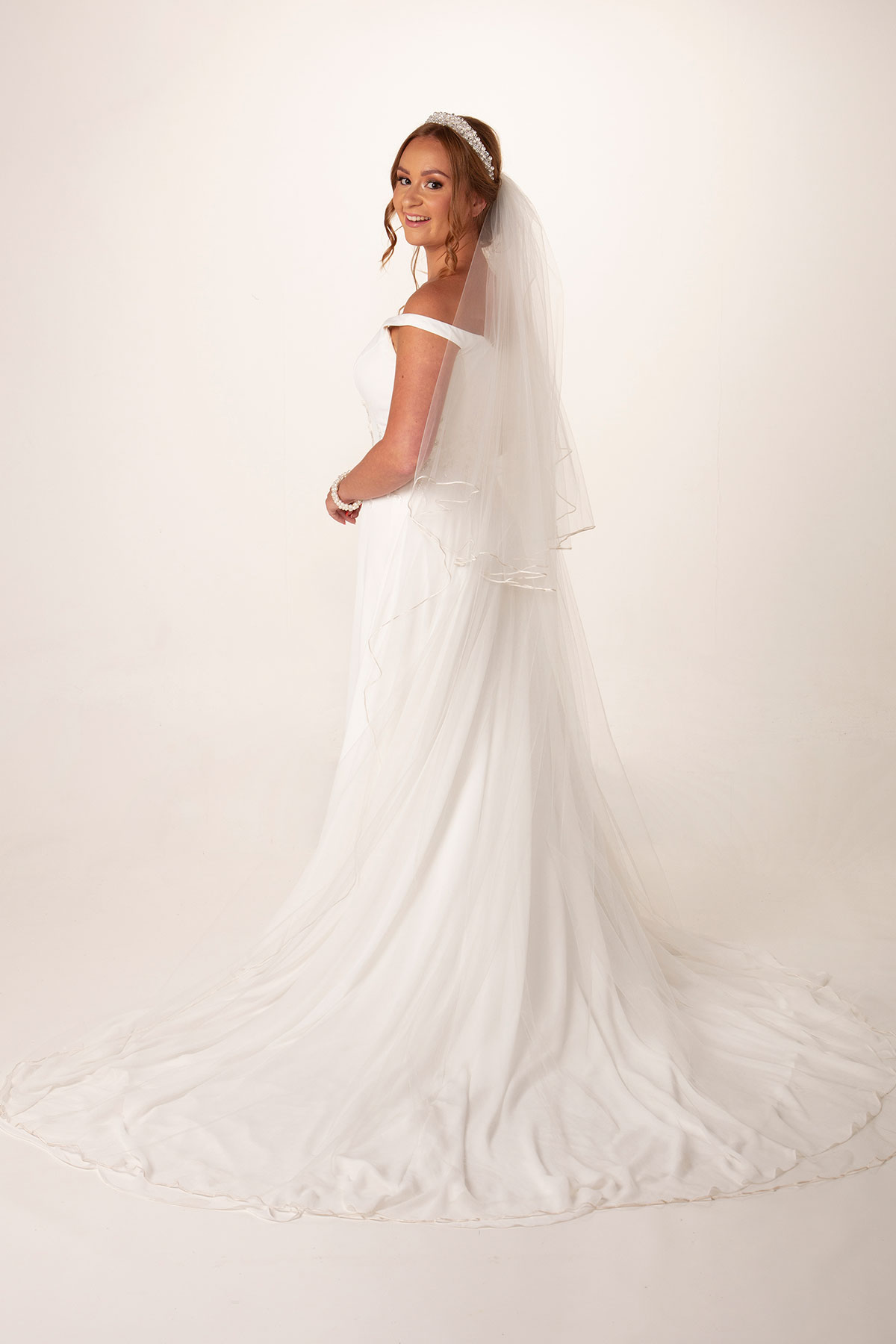 Bride wearing a long wedding veil with a pearl and crystal bridal headpiece by Baba-C Designs.