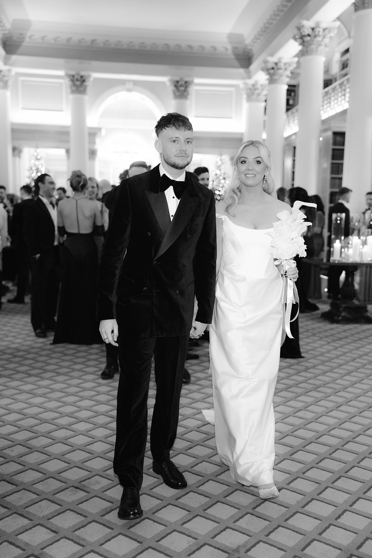 Bride and groom walking hand in hand through The Signet Library during their wedding reception