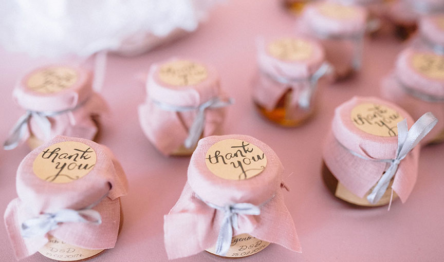 Miniature jam jar wedding favours on a pink linen tablecloth