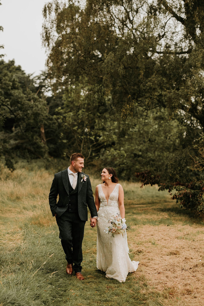 a bride and groom Matt Fagerson walking hand in hand in the grounds of Dunglass Estate