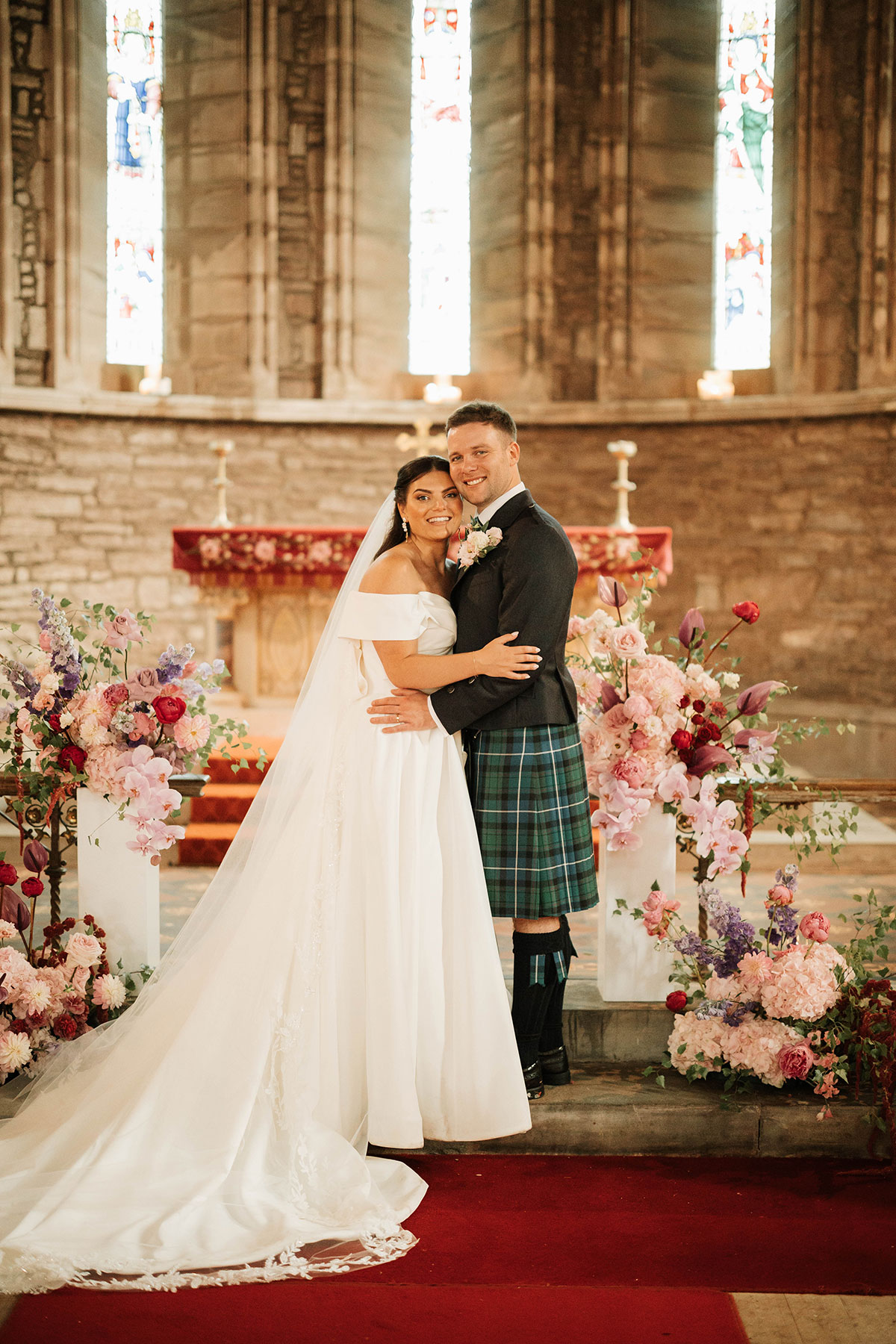 Bride and groom at altar in St Palladius Church Drumtochty Castle wedding ceremony with floral arrangements