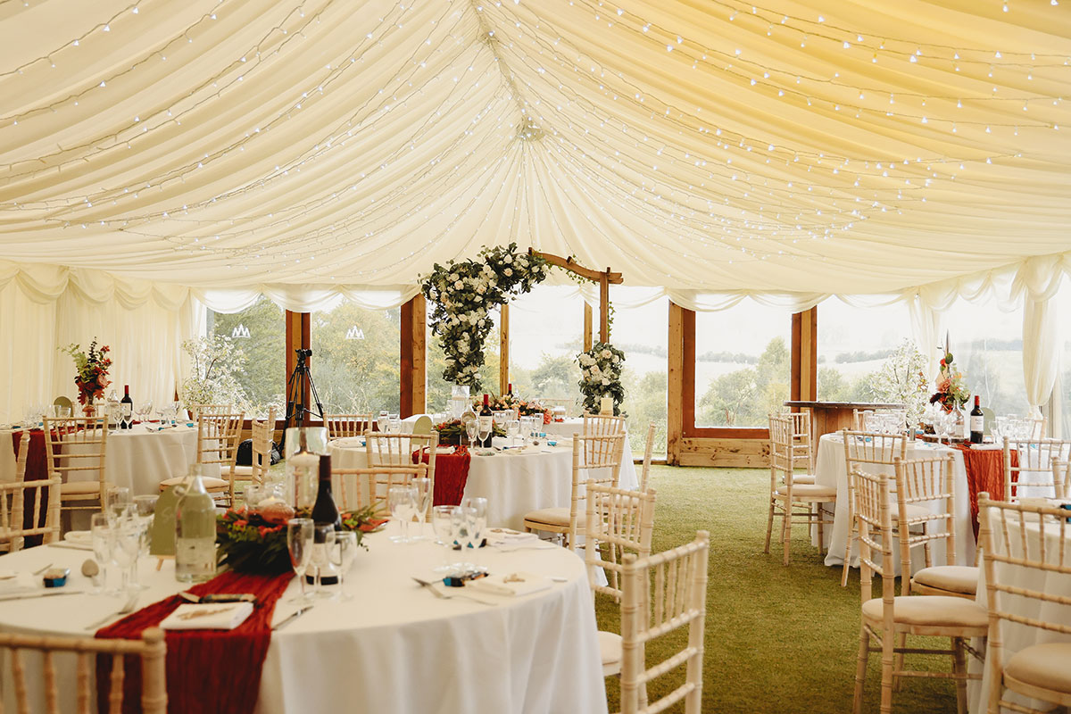 Wedding reception marquee with round tables, fairy lights and floral décor at a Scottish countryside wedding venue