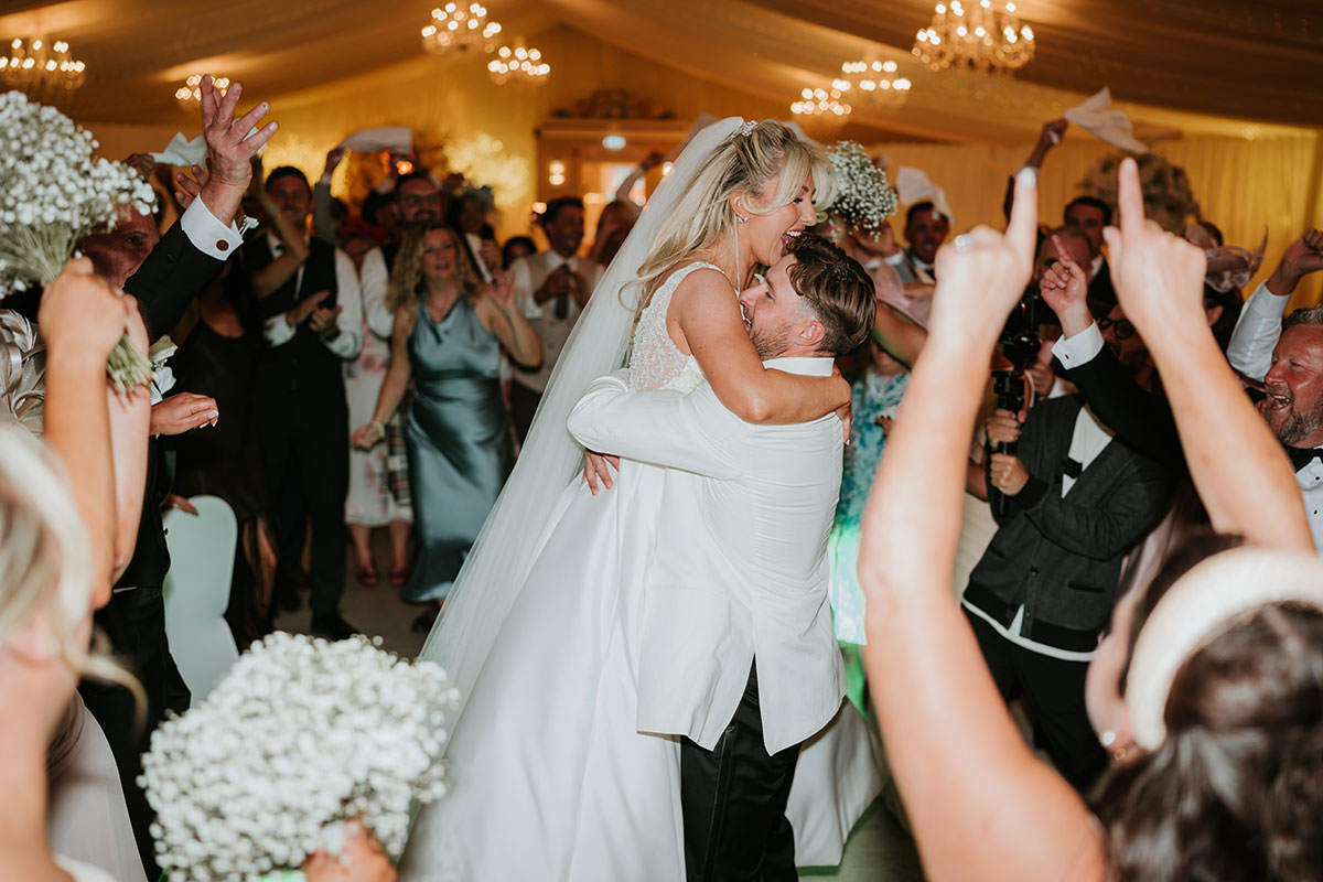 Groom lifting bride during lively dancefloor moment at Ingliston Country Club wedding reception