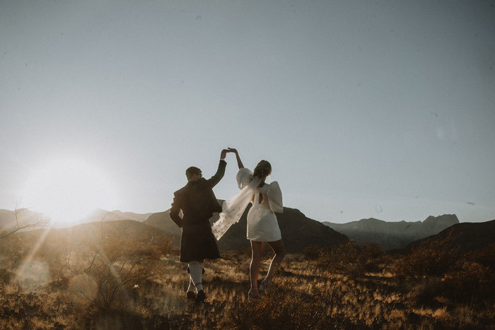 bride and groom dance in las vegas desert with sunset in the background