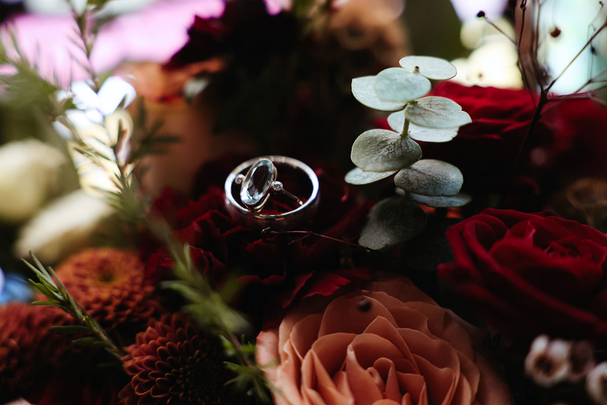 two rings sitting on top of a rose surrounding by other flowers