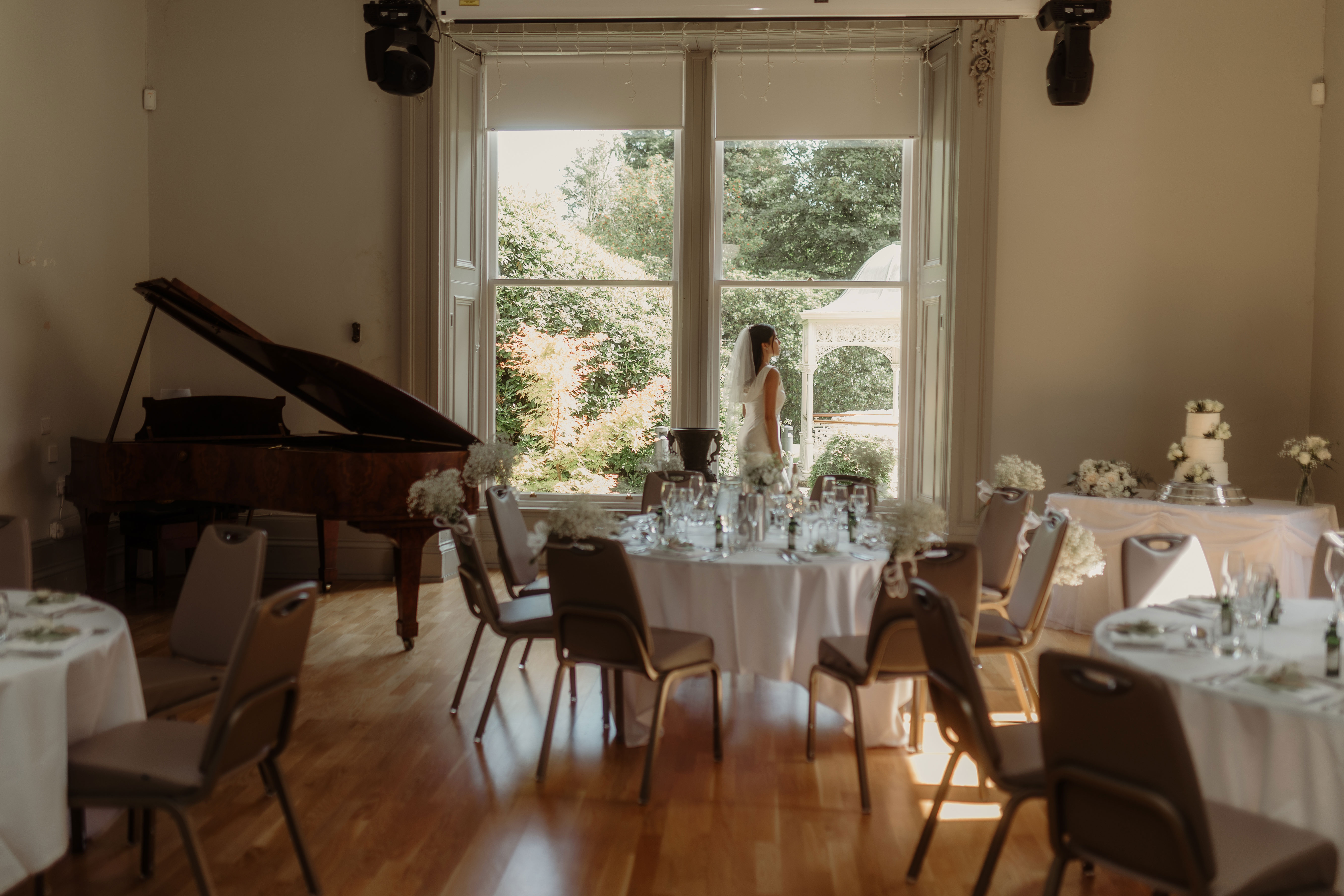 bride looks out of window in dinner room set up for a wedding at kilmardinny house