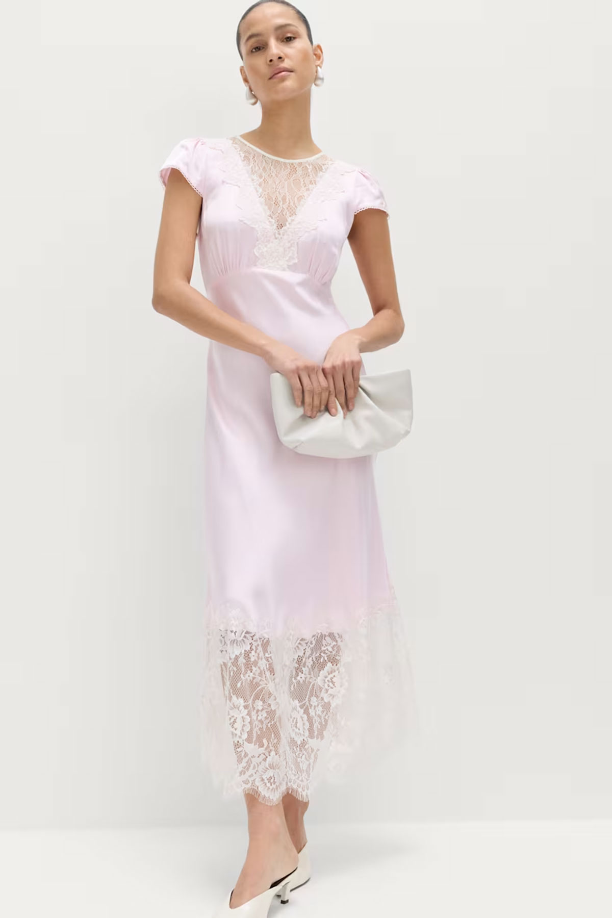 Blush pink satin midi dress with lace panel detailing and short sleeves styled with clutch bag in a studio setting