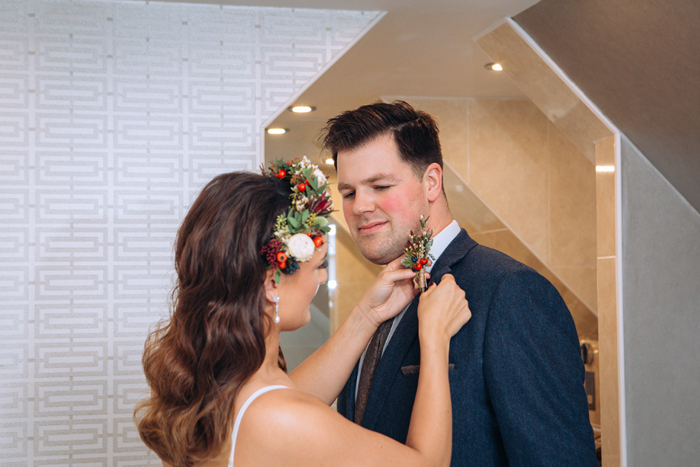 Bride helping groom put his buttonhole in his lapel