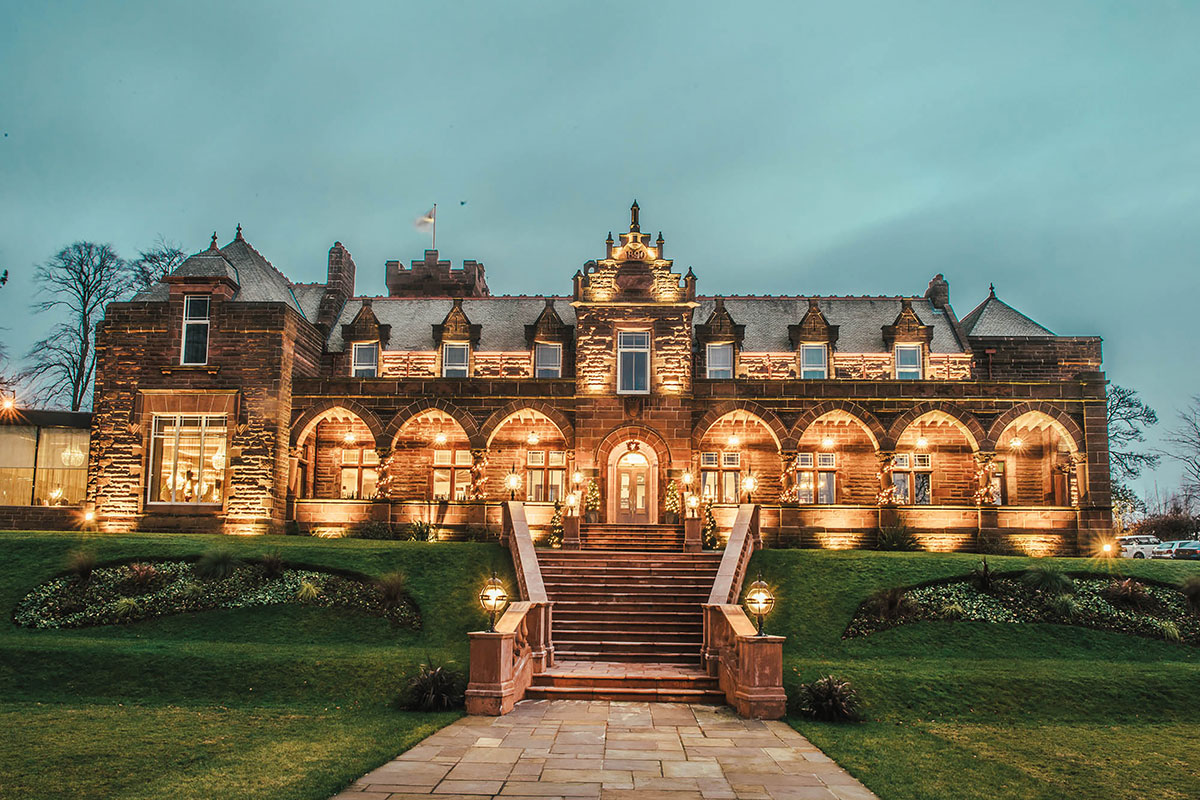 exterior view of brown brick building, lighting up the darker evening sky with warm lighting