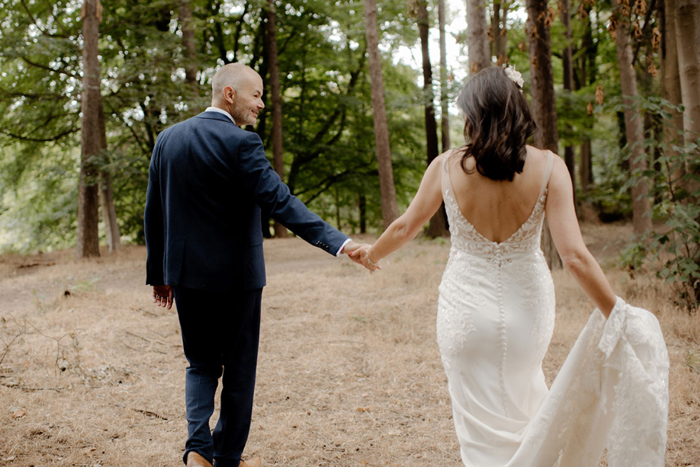 Couple portraits of bride and groom walking through woodland area