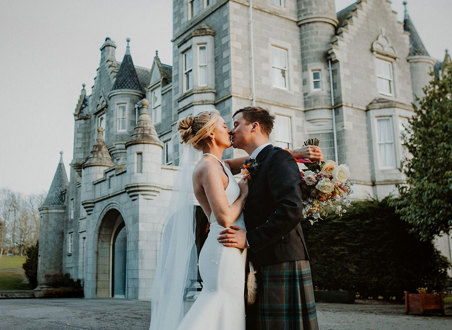 bride and groom kiss in front of ardoe house
