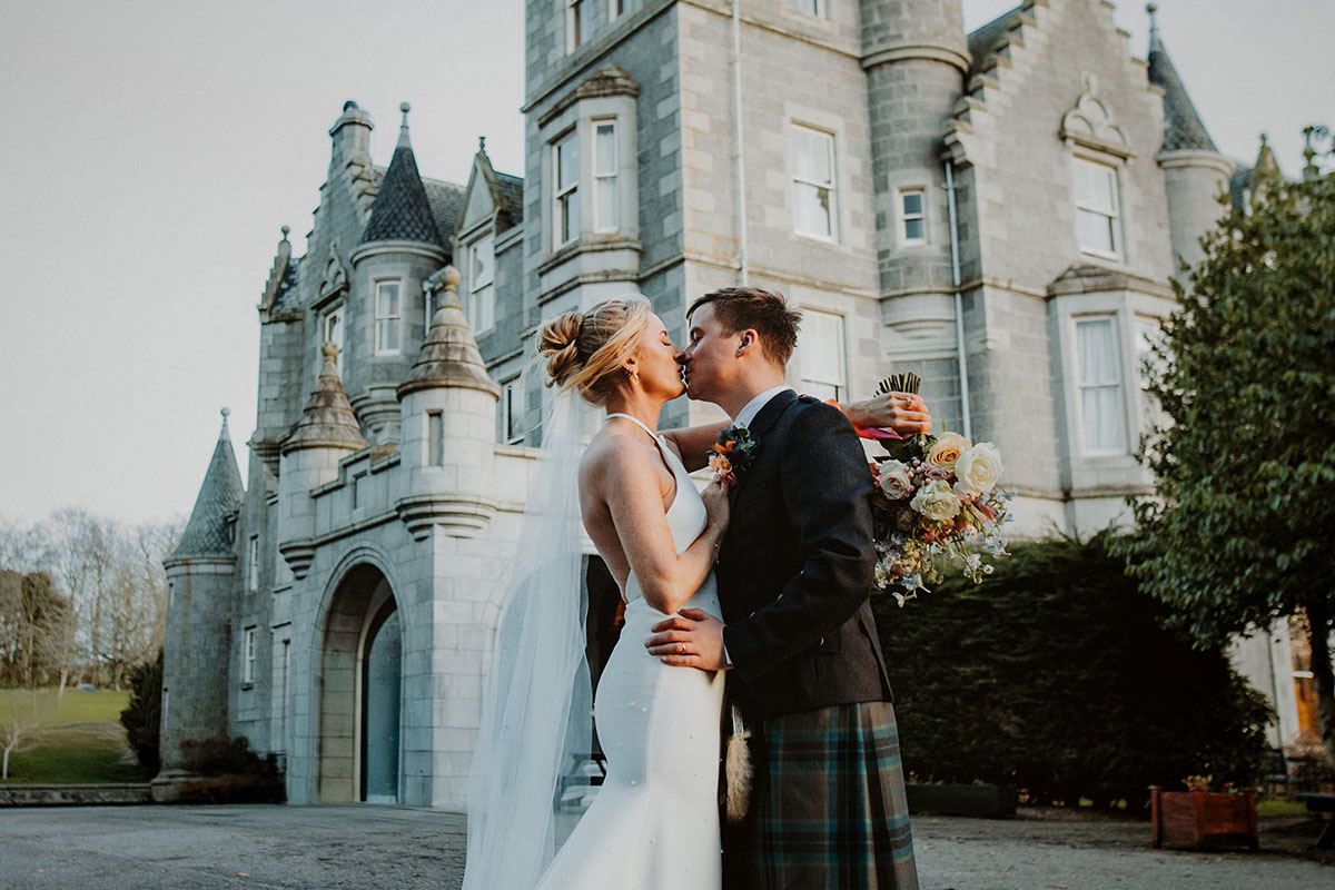 bride and groom kiss in front of ardoe house