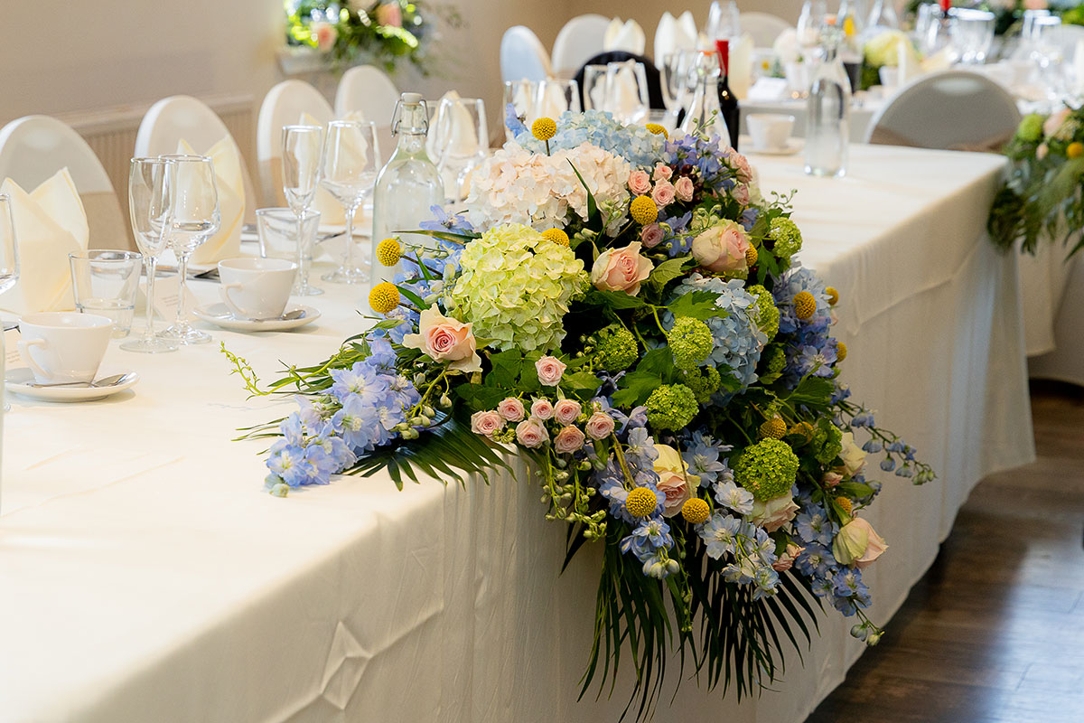 Wedding top table at The River Inn decorated with blue, green and blush floral arrangements.