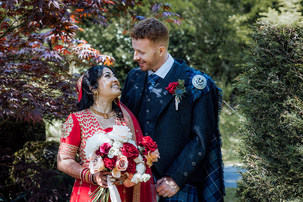Bride and groom posing together in the gardens of Atholl Palace Hotel following their Scottish and Indian fusion wedding ceremony