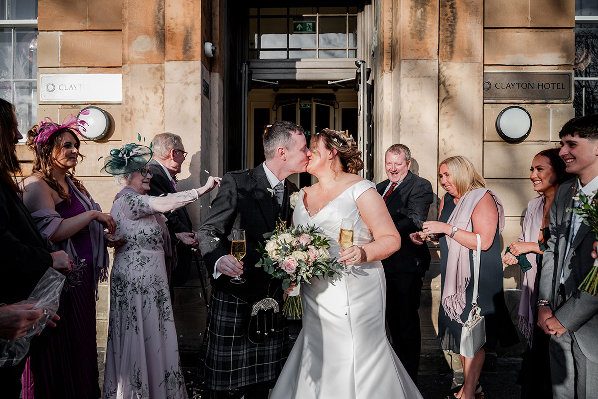 Newlyweds celebrate with guests outside the entrance of Clayton Hotel Glasgow after their wedding ceremony.