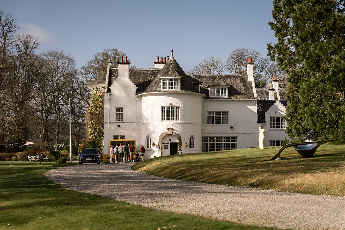 exterior of achnagairn castle on a sunny day with guests gathering outside