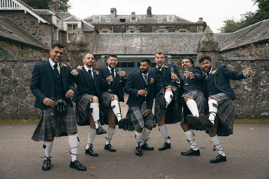 A group of men in kilts holding wine glasses.