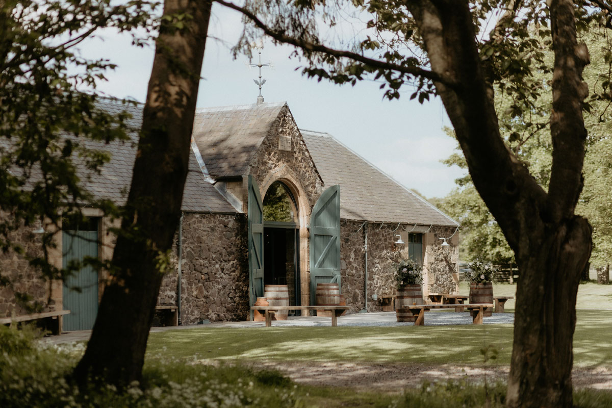 Stone barn exterior at The Byre at Inchyra in Perthshire, framed by mature trees and countryside.