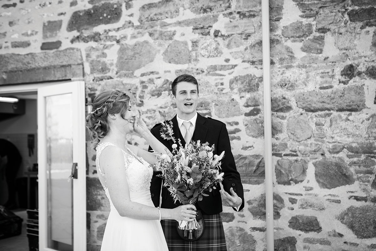 Bride holding her bouquet laughs with her groom following their ceremony