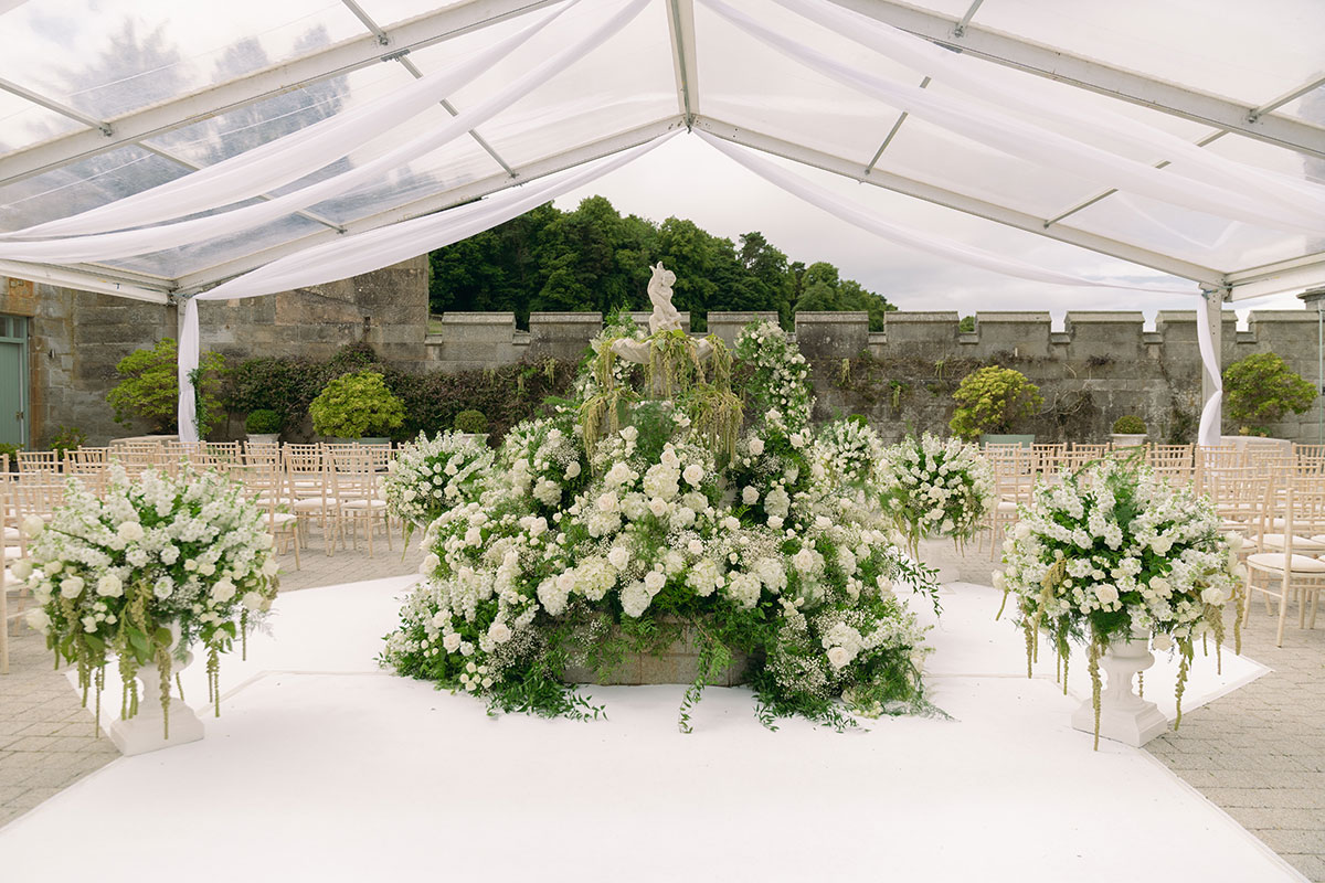 Dundas Castle courtyard ceremony setup with white draped canopy, floral arrangements and fountain centrepiece.
