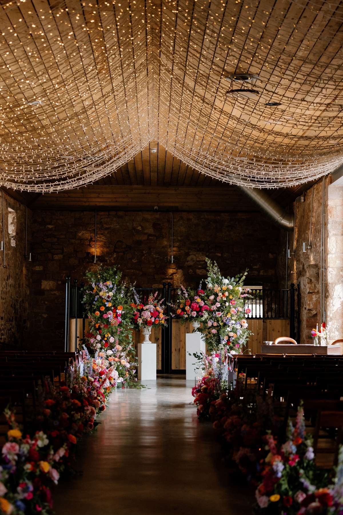 Wedding ceremony entrance styling with floral pedestal arrangements, confetti station and fairy lights at Falside Mill