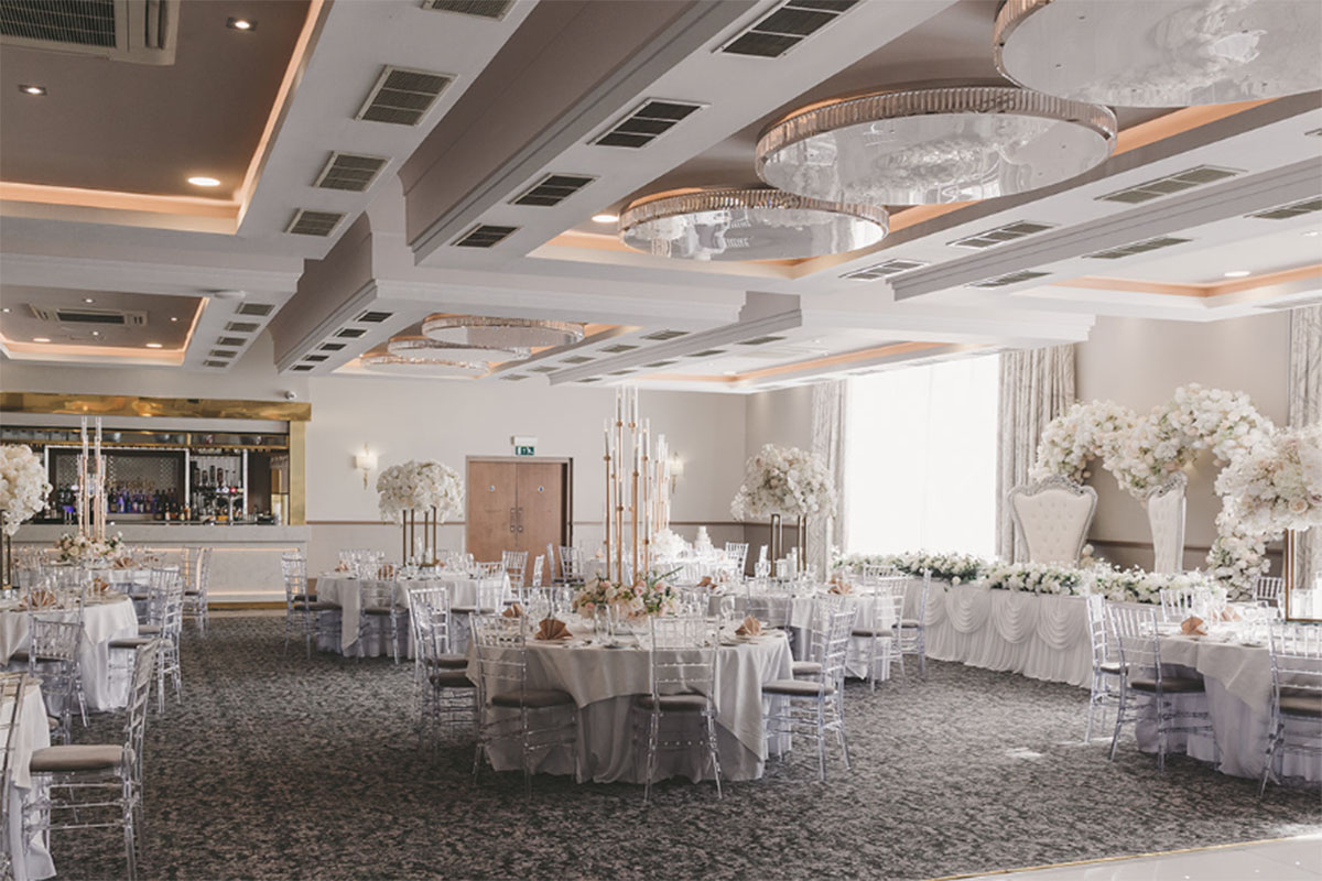 Riverside Lodge Hotel ballroom set for a wedding reception with round tables, floral centrepieces and modern ceiling lighting.