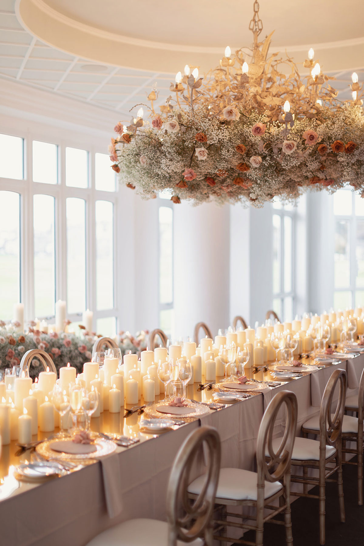 Old Course Hotel conservatory wedding reception with long tables, hundreds of pillar candles and overhead floral installation in St Andrews
