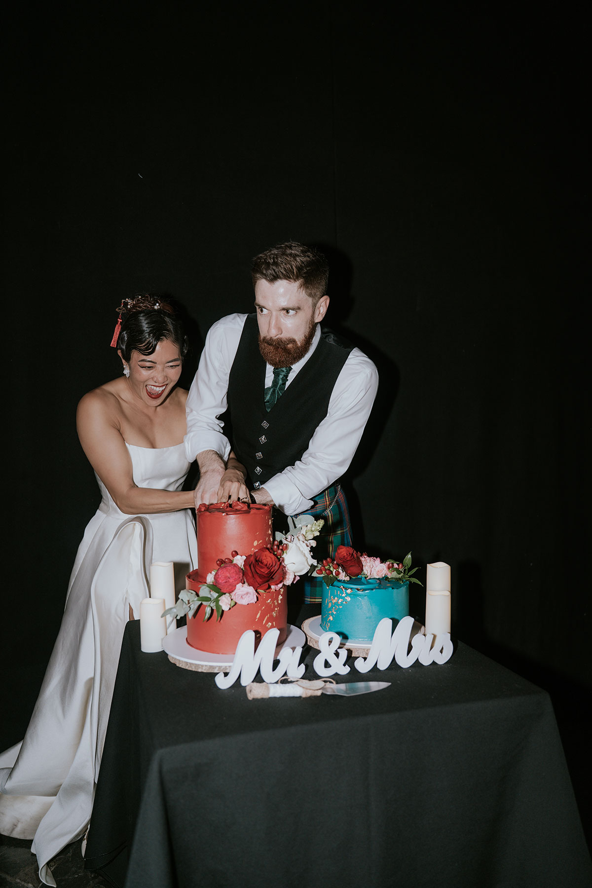 Bride and groom cutting colourful wedding cakes at Barras Art and Design Glasgow reception
