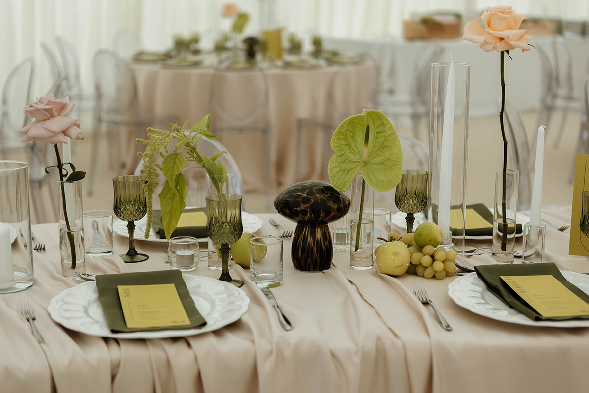 Wedding table styling with blush linen, green glassware, apples and grapes, and modern floral centrepieces in Ayrshire marquee.