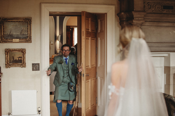 A Man In A Kilt Walking Through A Door To Greet A Bride