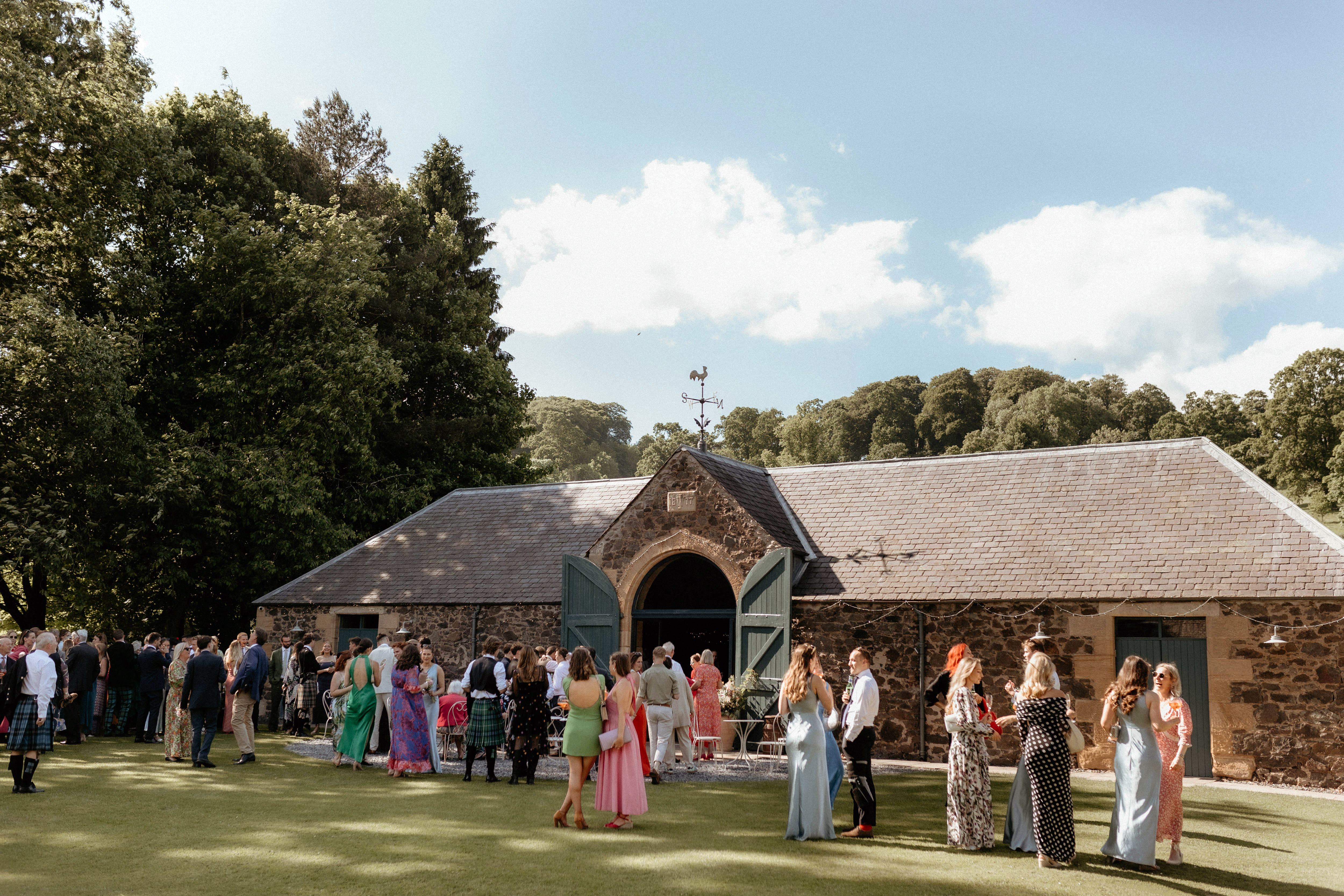 The exterior of The Byre at Inchyra on a sunny day with guests outside