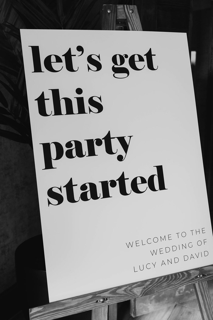 A white sign with black text that reads "let's get this party started"