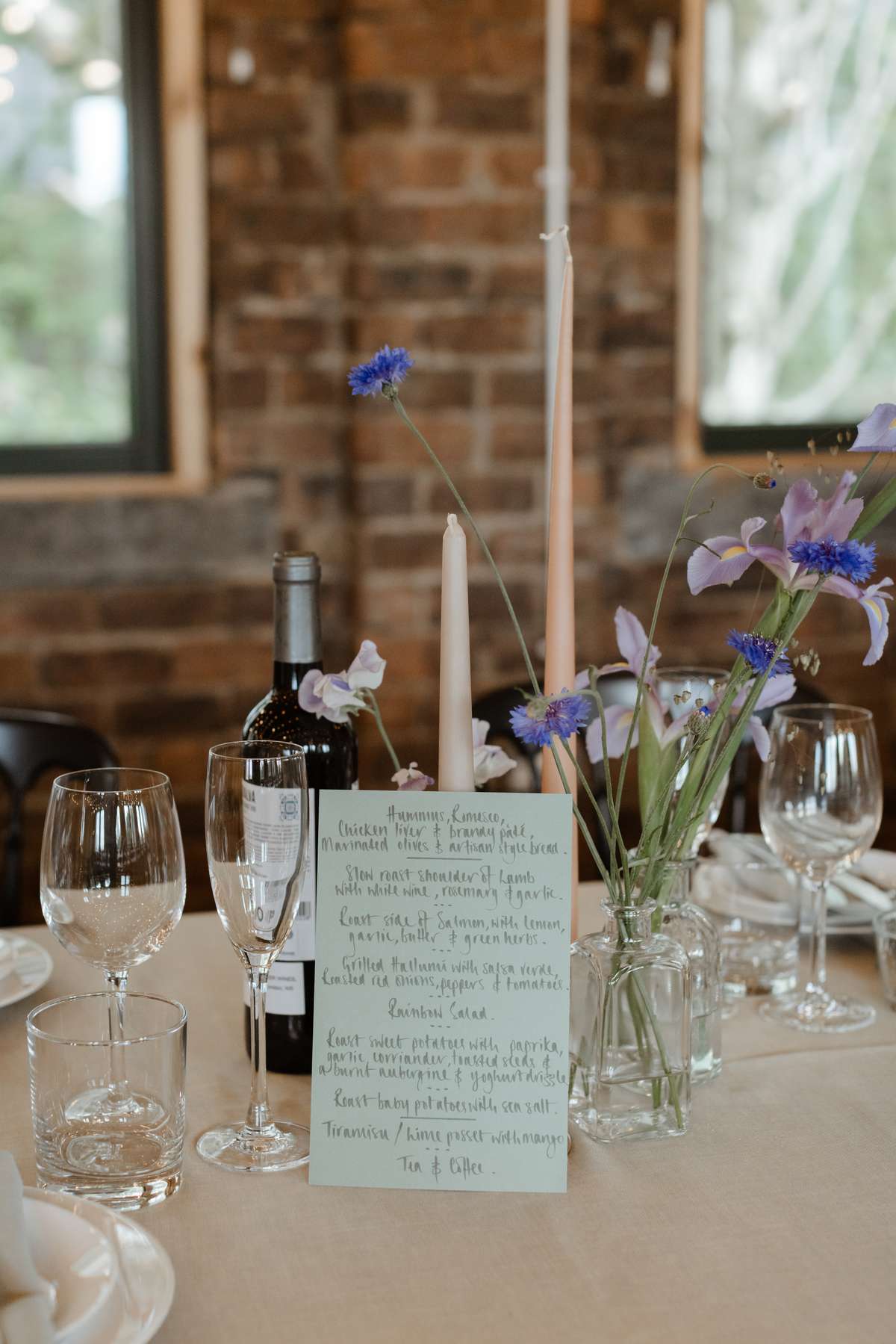 Wedding table styling with bud vases, candles and colourful flowers