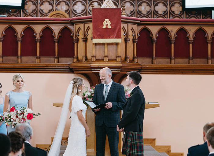 A bride and groom at the alter of a church during their ceremony