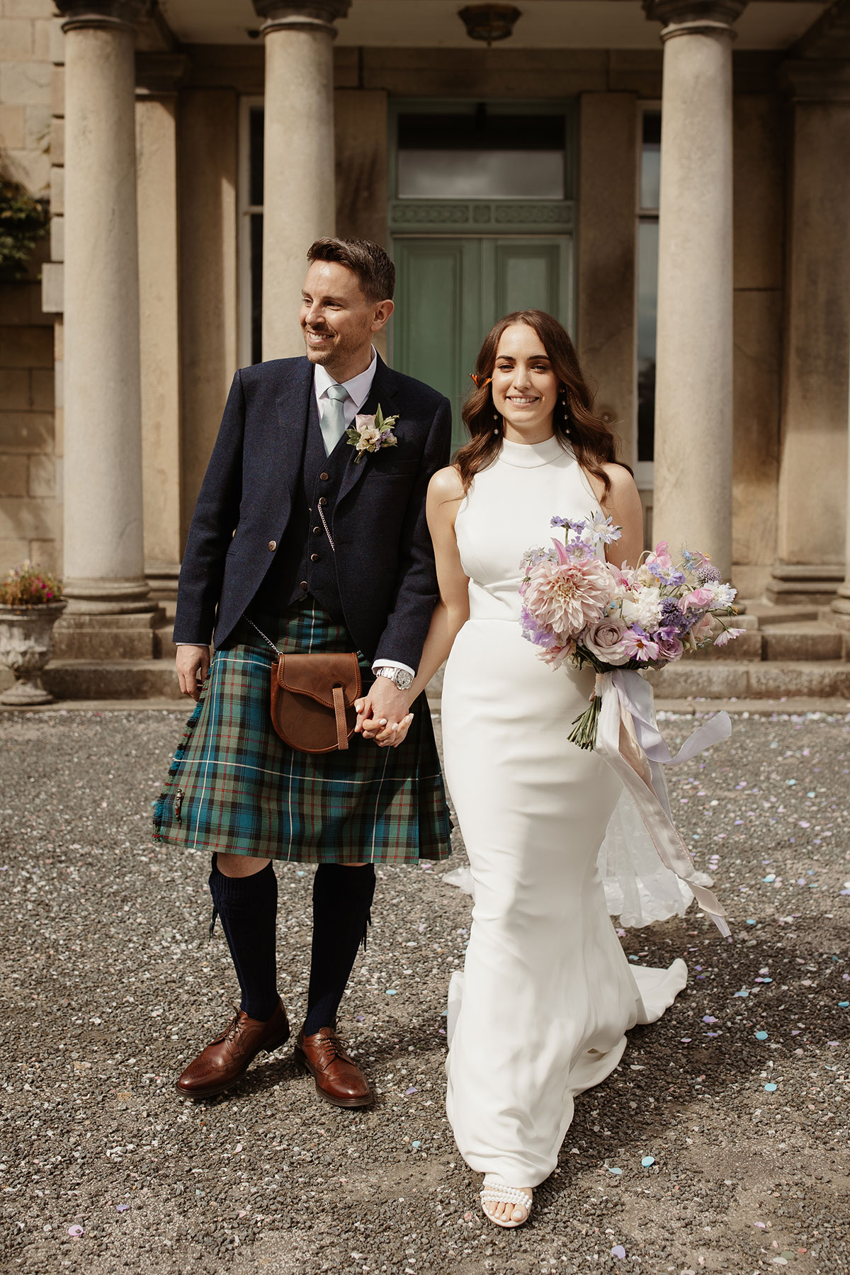 a bride and groom walking hand in hand outside Netherdale House