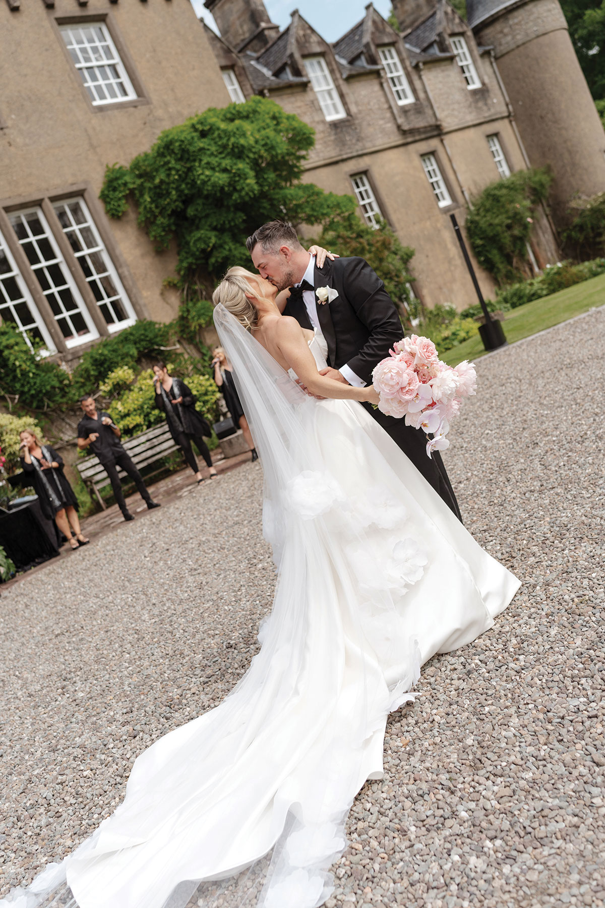 Bride and groom share their first kiss outside Boturich Castle while GeO Gospel Choir performs in the background.