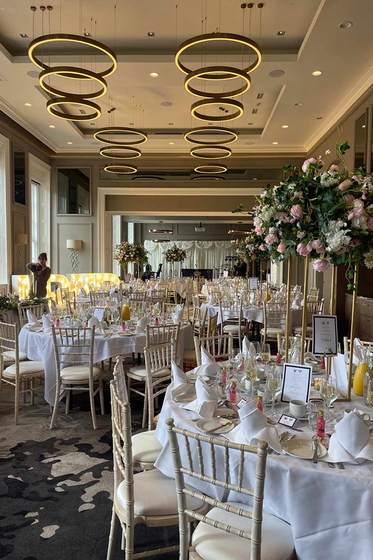 Wedding reception setup at Clayton Hotel Glasgow with round tables, floral centrepieces and modern ring lighting