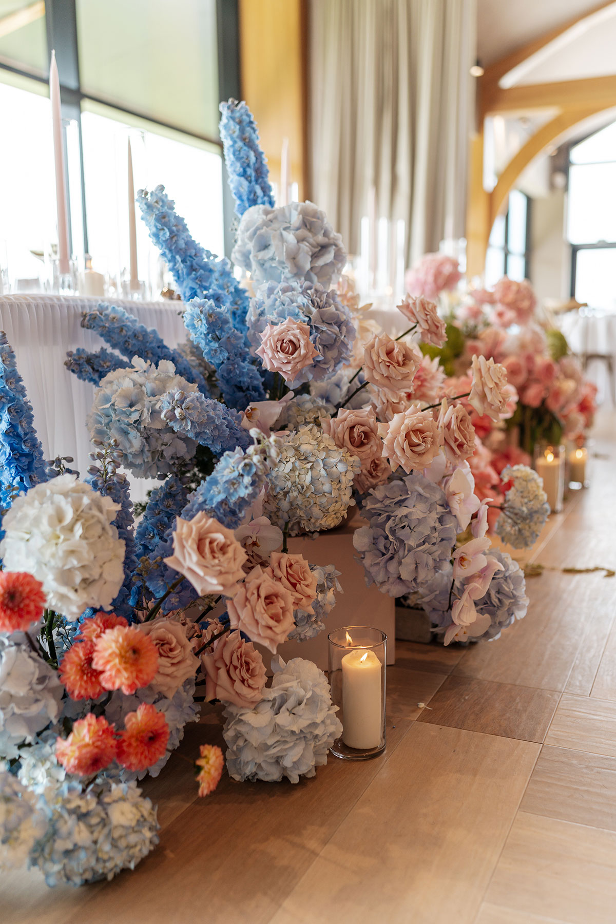 Colourful blue, pink and white floral aisle arrangements by Fiori Glasgow inside the Boturich Castle wedding reception space.