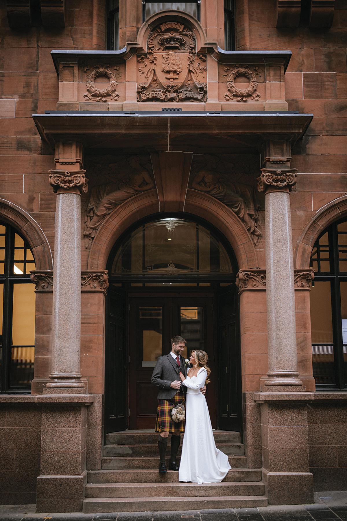 Wedding couple outside the historic sandstone entrance of The Collector’s Hall, a city centre wedding venue in Glasgow.