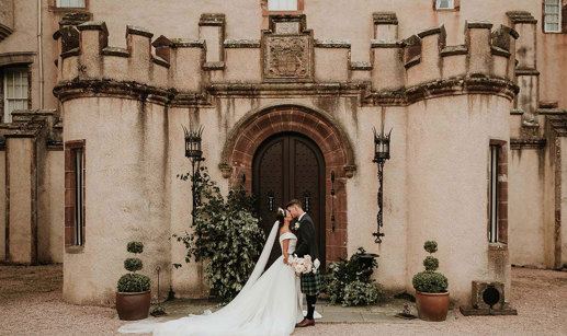 bride and groom kiss at the doors of fyvie castle on wedding day