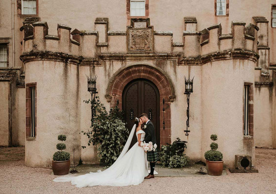 bride and groom kiss at the doors of fyvie castle on wedding day