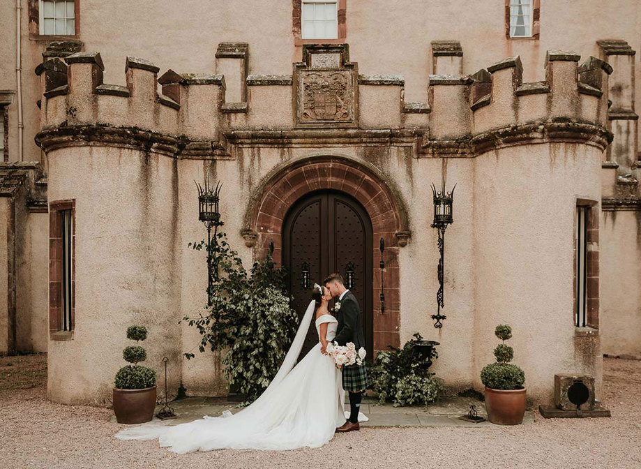 bride and groom kiss at the doors of fyvie castle on wedding day
