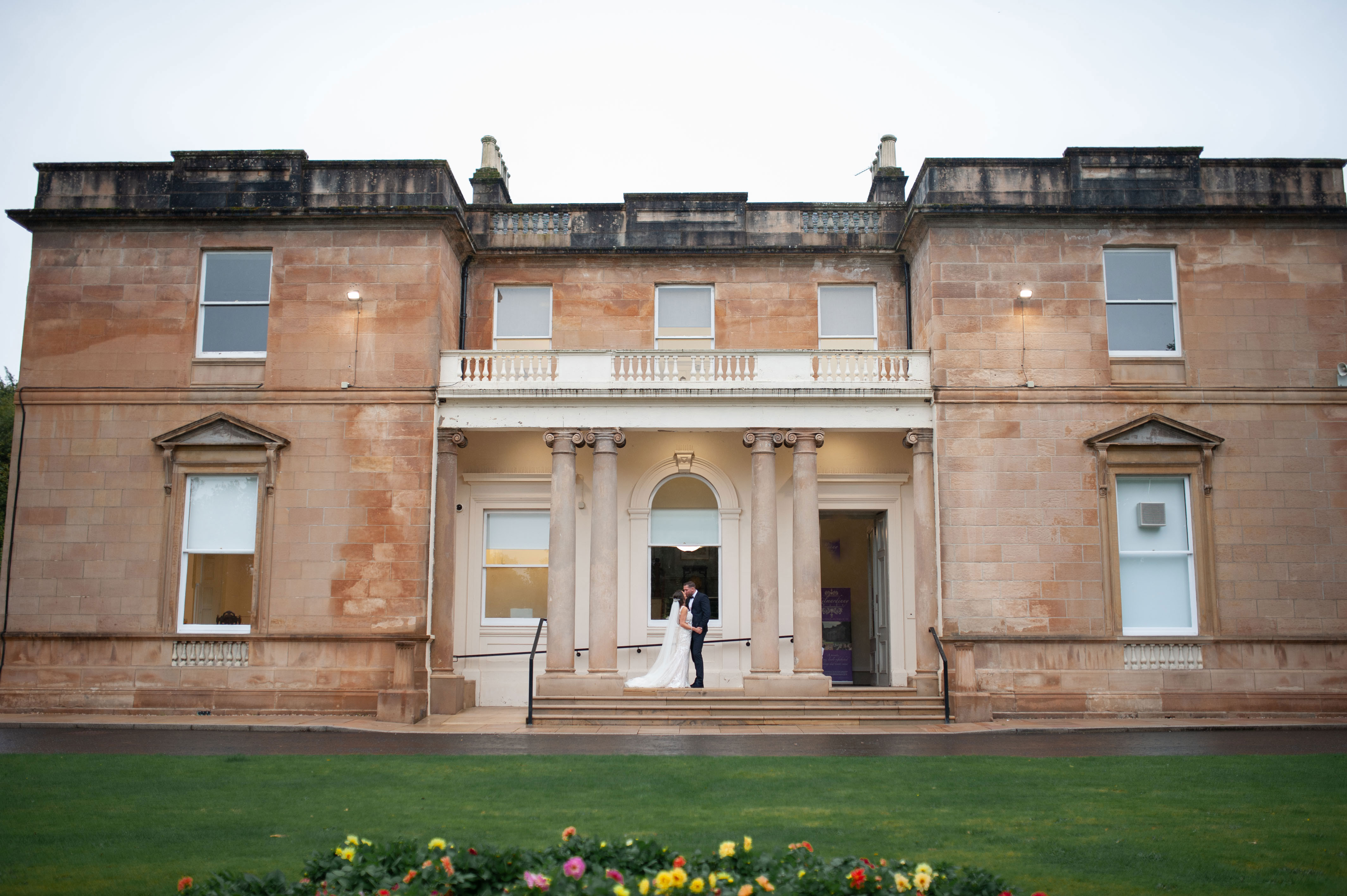 exterior of kilmardinny house with bride and groom kissing in front