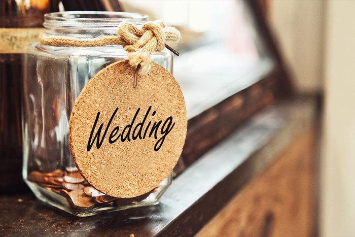 glass jar of coins with a 'wedding' label tied around the neck
