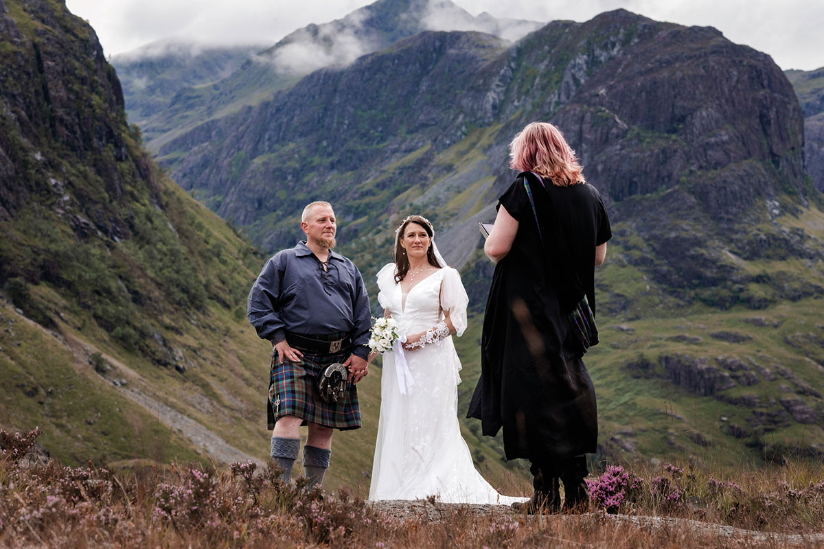 Outdoor Scottish elopement ceremony with a couple and celebrant in a dramatic Highland mountain valley