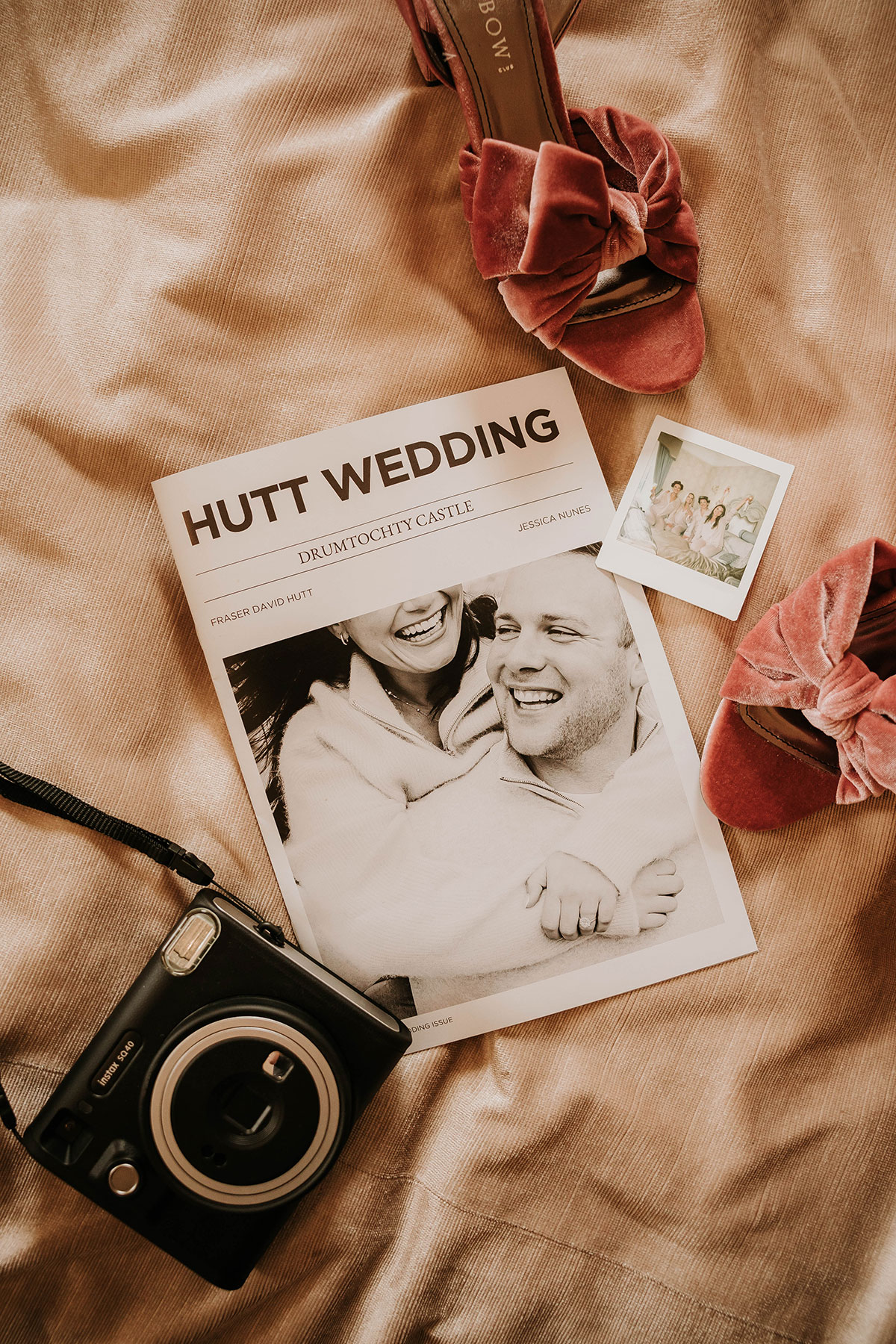 Wedding flat lay with personalised newspaper, pink bridal shoes and instant camera at Drumtochty Castle wedding