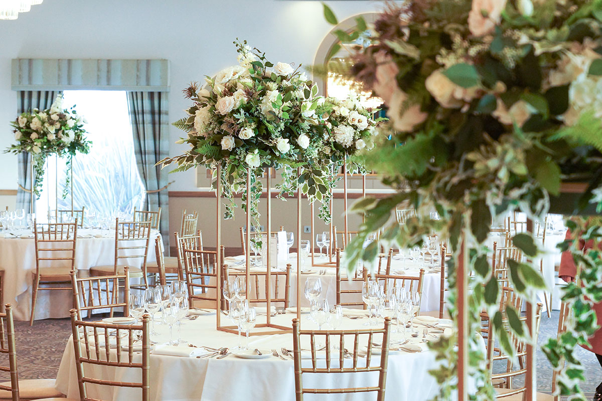 Kyle Suite at The Waterside Hotel set for a wedding reception with gold Chiavari chairs, tall floral centrepieces and round tables.