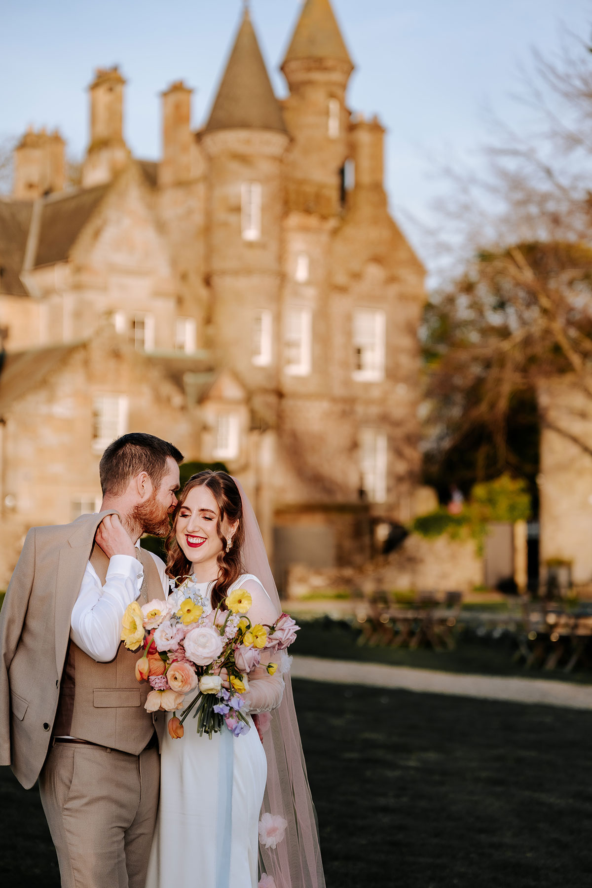 a smiling bride and groom posing in sunlight in the garden of Carlowrie Castle wedding venue Edinburgh